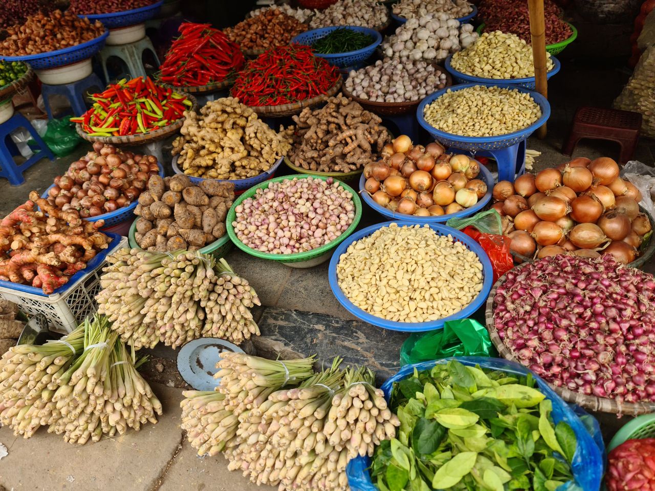 Colorful display of fresh vegetables and spices at a local market in Hanoi, Vietnam.